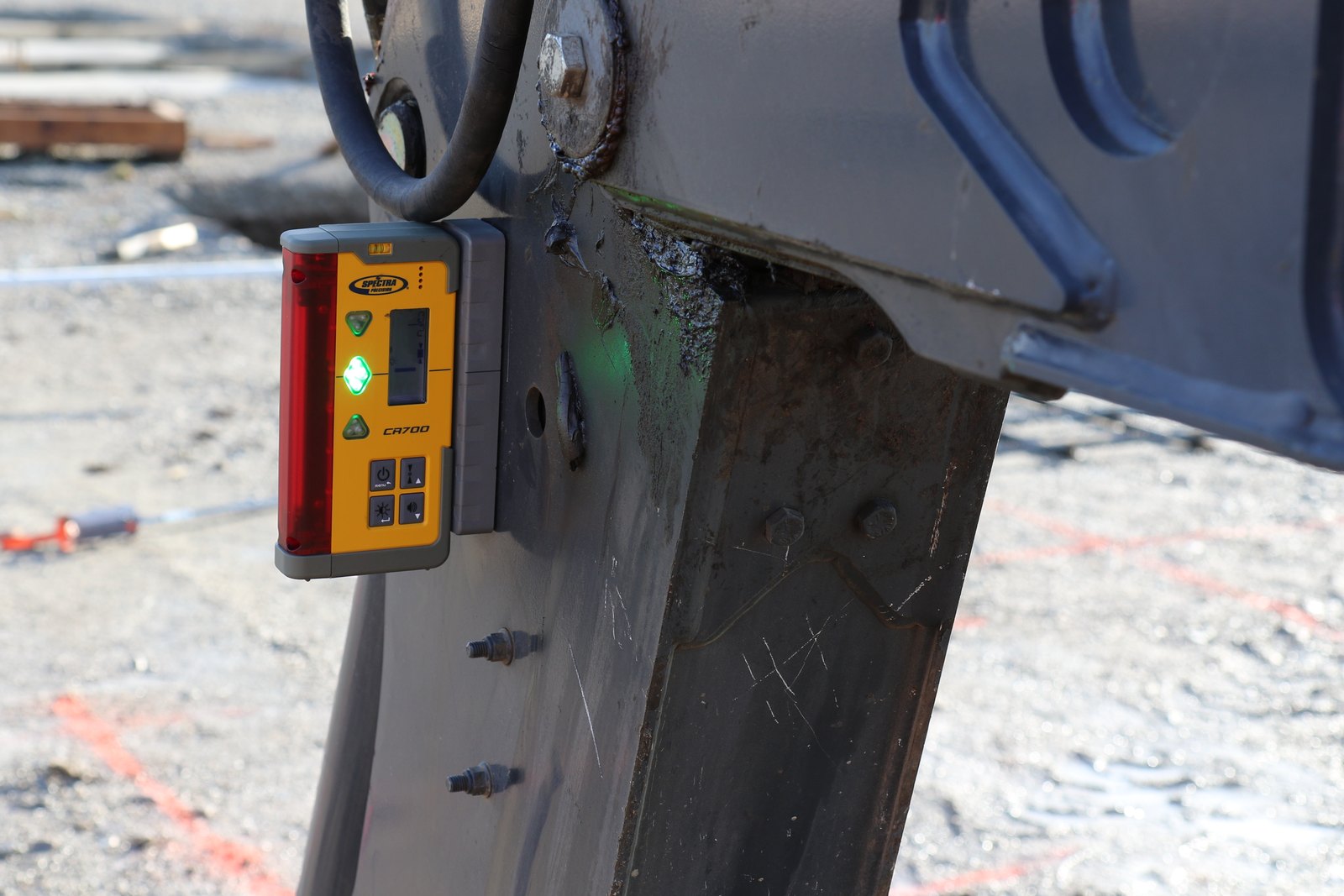 Spectra CR700 laser receiver magnet-mounted to an excavator arm with the green on-grade LED lit